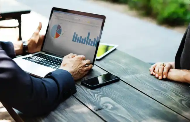 Personne qui consulte des informations d'analyse sur un ordinateur portable tout en étant assise à une table.