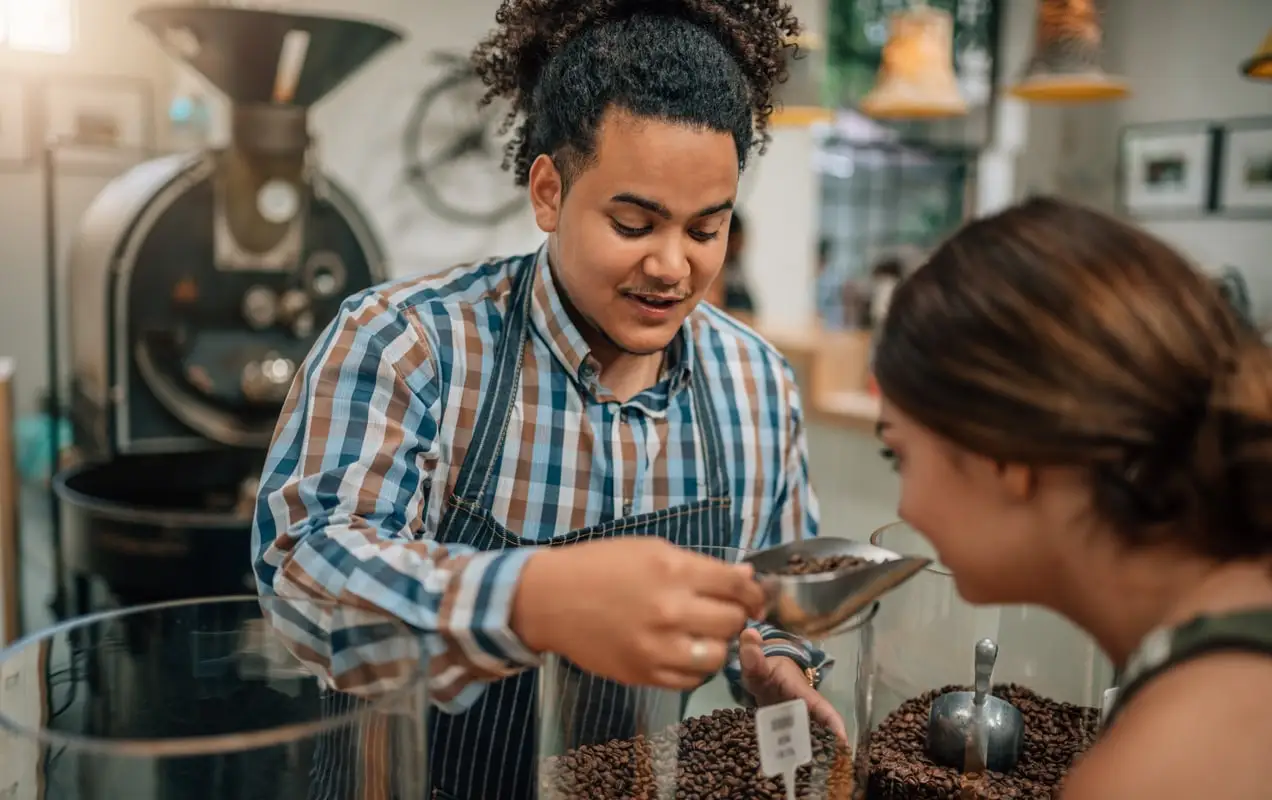 dueño de una cafetería sirviendo café a un cliente