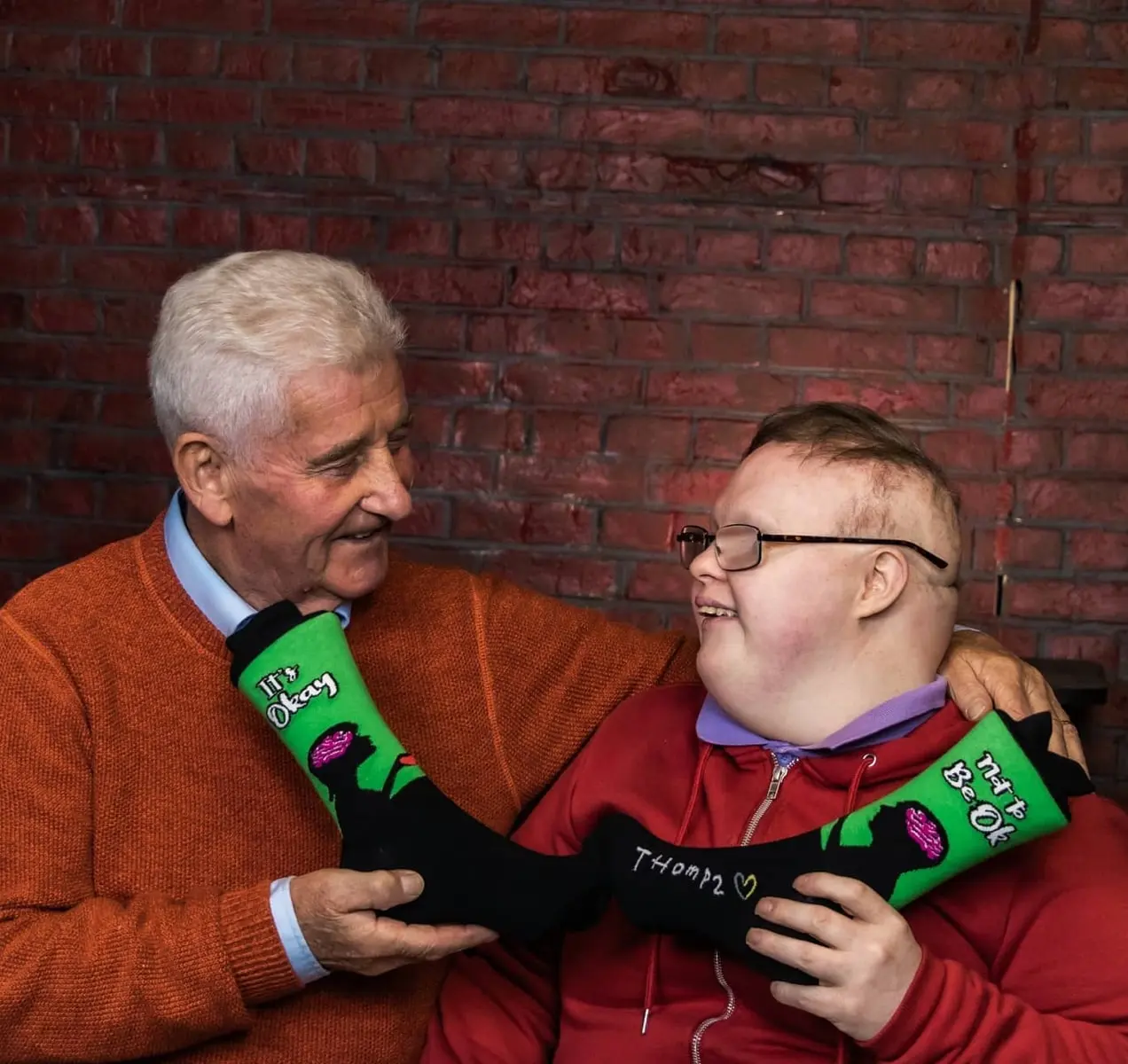 Thomas et son père avec une paire de chaussettes qui disent : "C'est normal de ne pas aller bien."