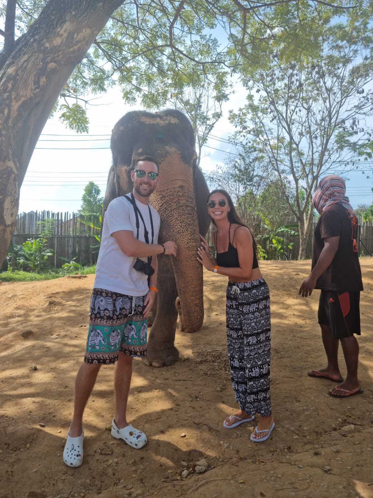 Un hombre y una mujer parados frente a un elefante.