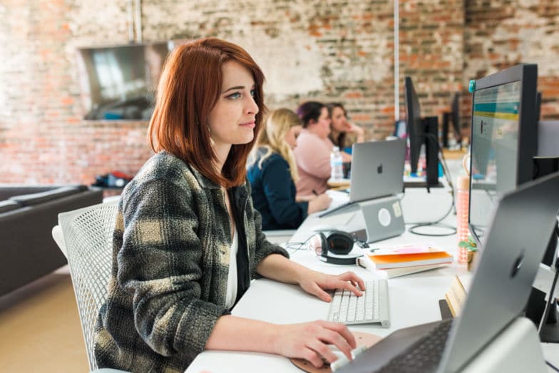 Establecimiento de límites profesionales con los clientes. La mujer se sienta en un escritorio largo trabajando con otras tres mujeres que trabajan en colaboración en segundo plano