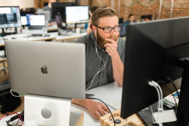 Un homme portant des lunettes regarde pensivement un écran d'ordinateur