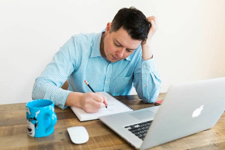 Fixer des limites professionnelles. L'homme dans une chemise bleue écrit à un bureau avec sa tête dans sa main