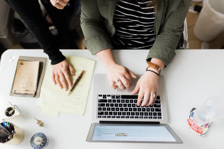 ketik tangan pada laptop di meja putih