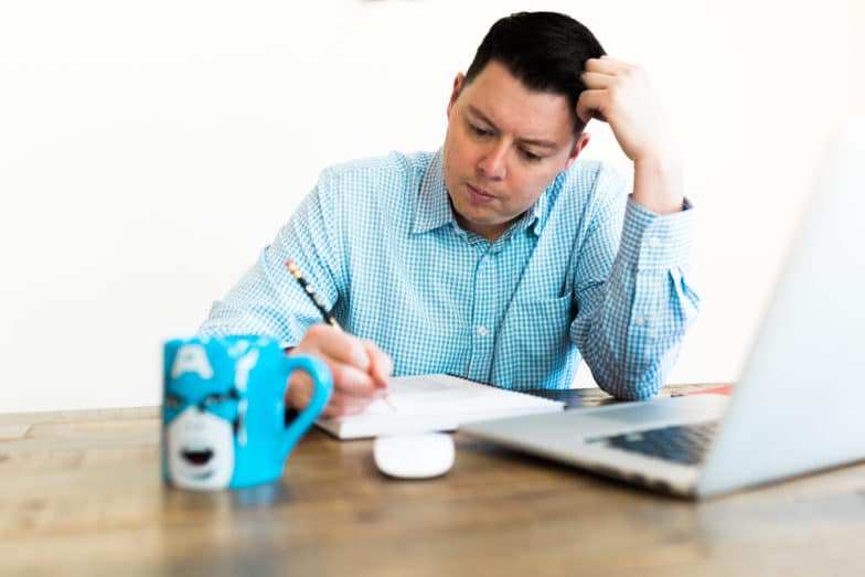 L'homme est assis au bureau travaillant sur ordinateur.