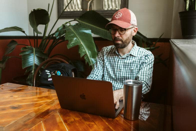 Ein Mann mit Baseballkappe arbeitet an einem Laptop