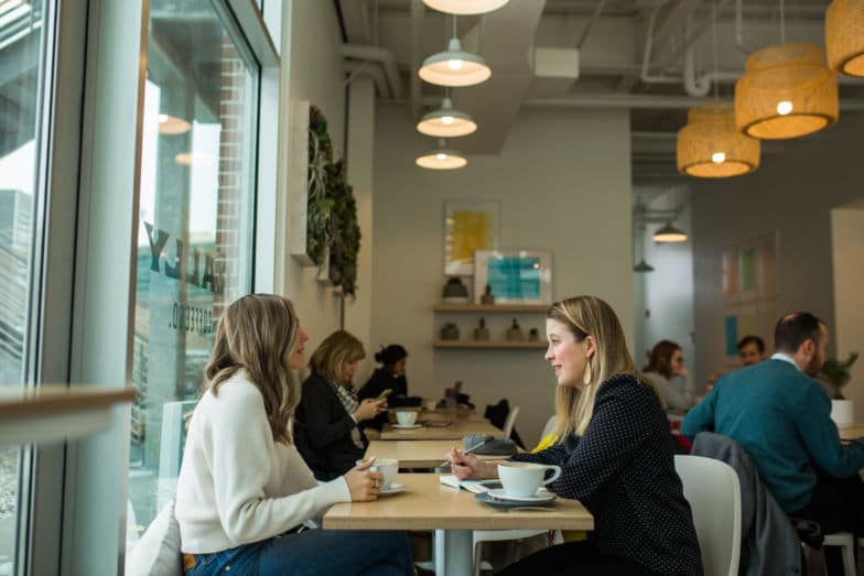 dos mujeres discuten un proyecto en una cafetería