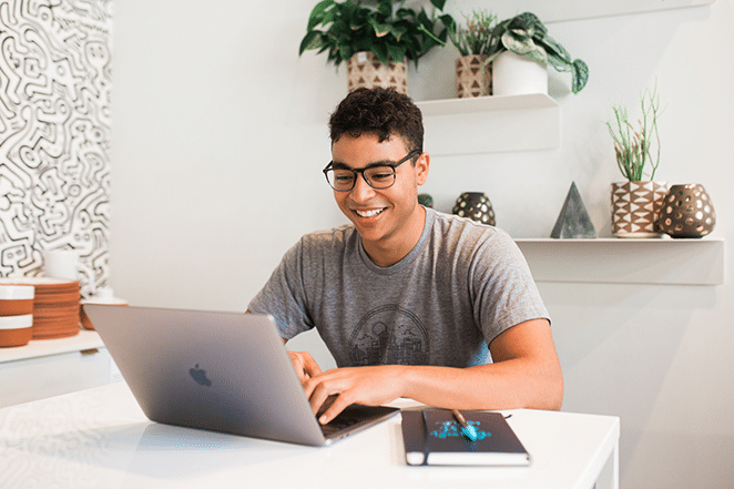 pessoa em espaço em branco brilhante no laptop e com notebook por perto