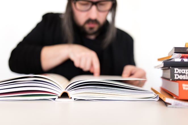 homme pointant sur un livre de design au bureau blanc