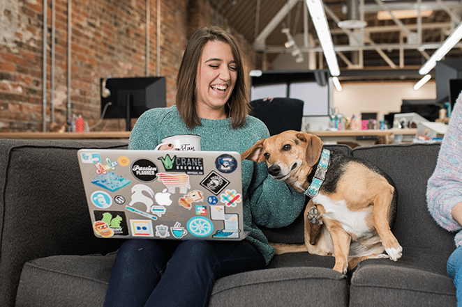 mujer y perro en el sofá con café y computadora portátil midiendo métricas de contenido