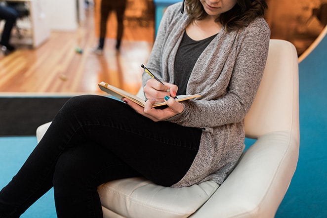 femme écrivant dans un rapport de cahier