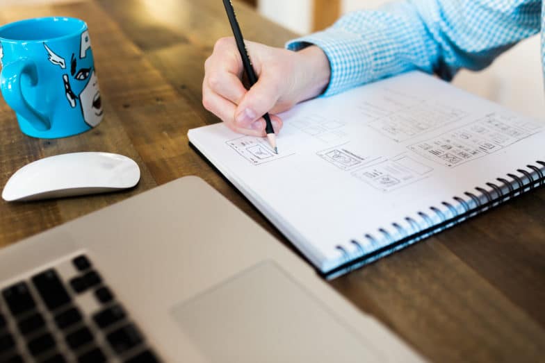 el hombre escribe en un cuaderno junto a una taza del Capitán América