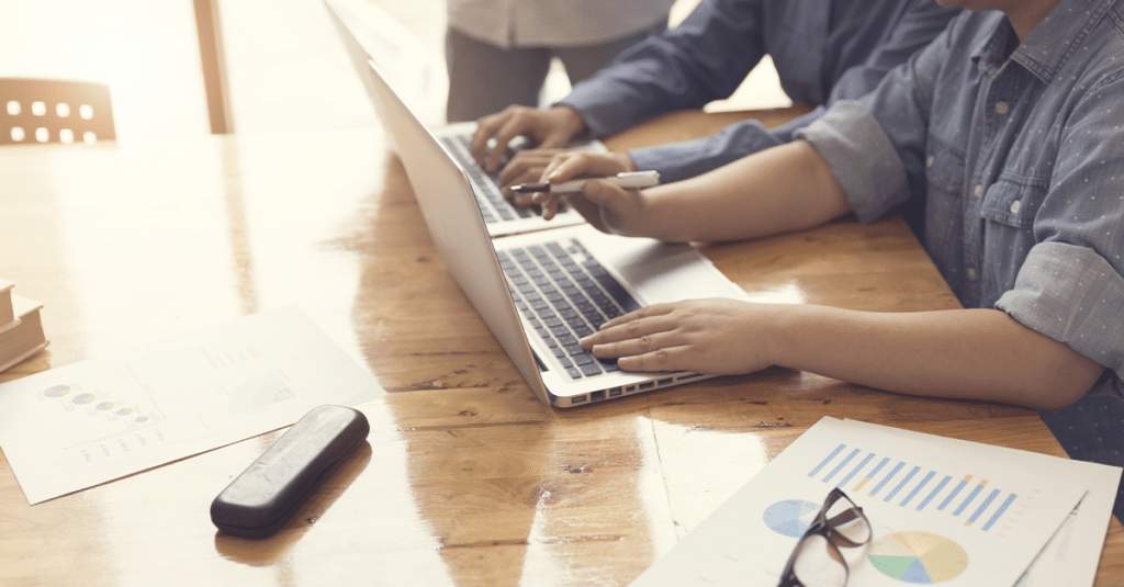 Dos personas trabajando en computadoras portátiles sentadas una al lado de la otra.