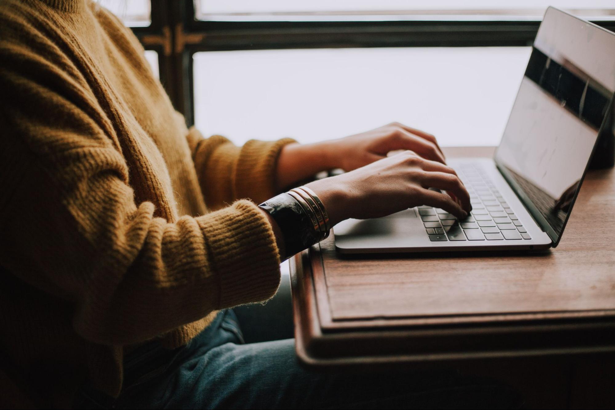 mujer trabajando en una mesa con una laptop