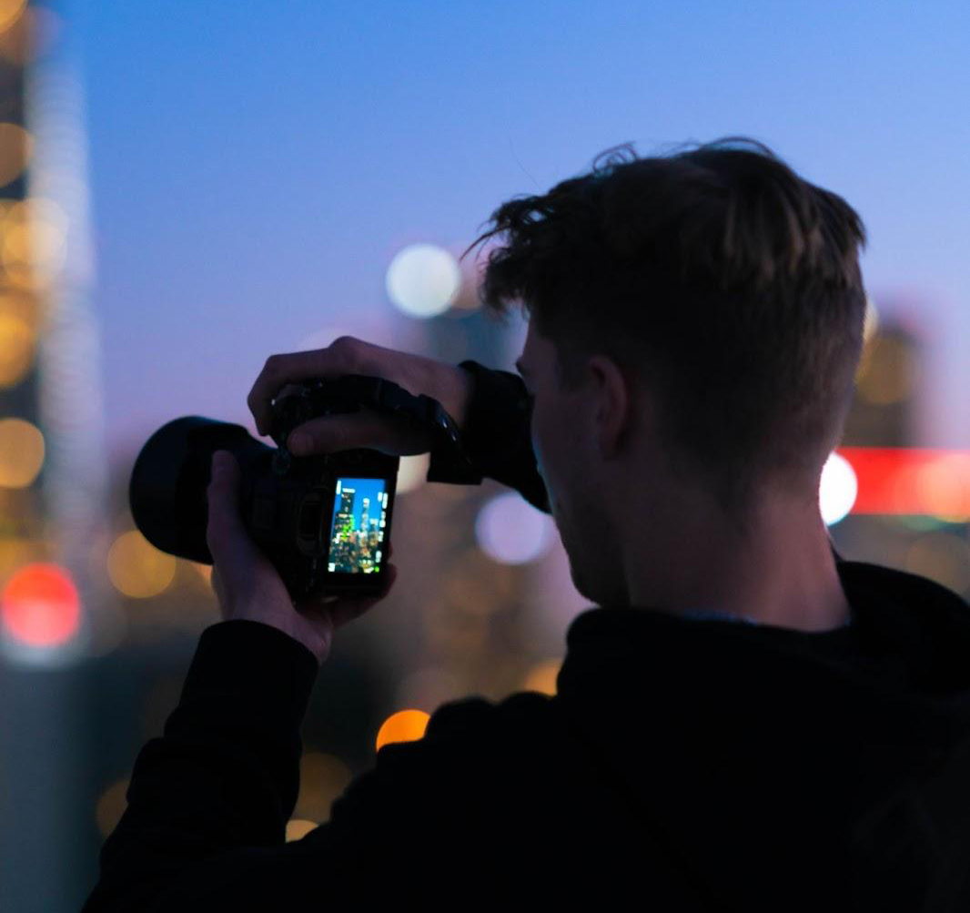 homem tirando uma foto de uma cidade à noite