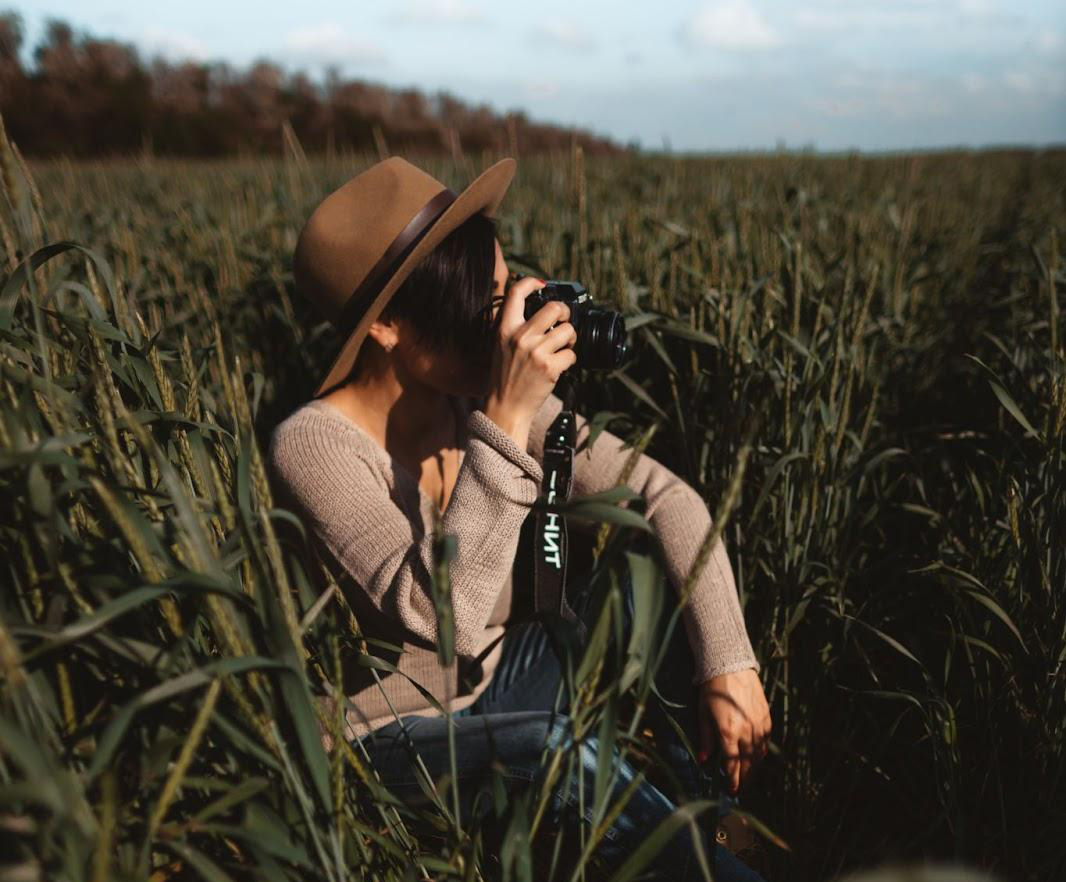 fotograf care face poze în natură într-un câmp