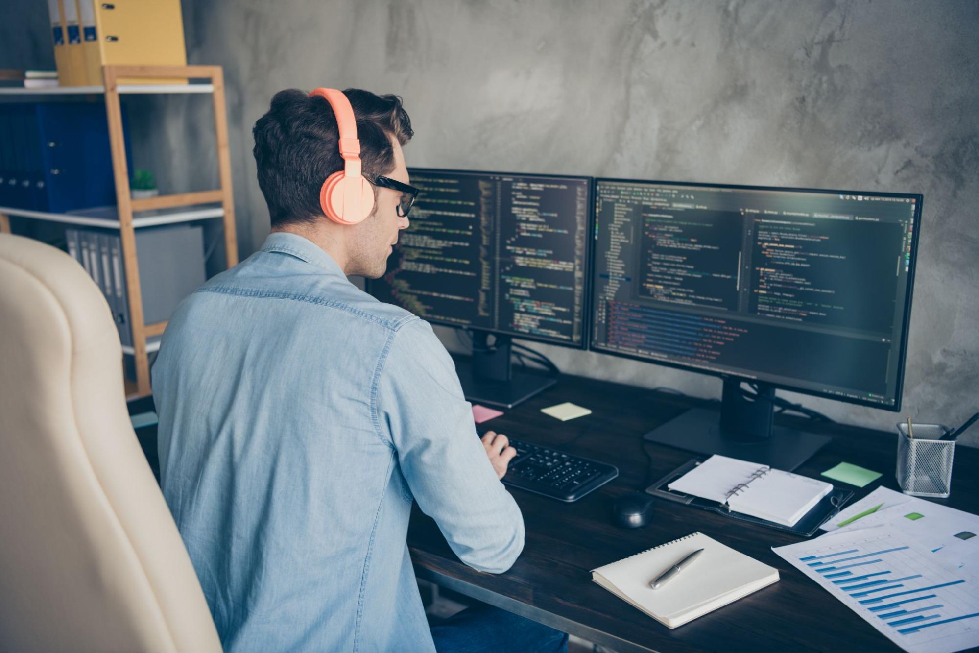 desenvolvedor trabalhando em duas telas de computador