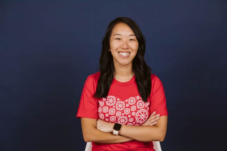 Una mujer con una camiseta roja Flywheel sonríe directamente a la cámara.