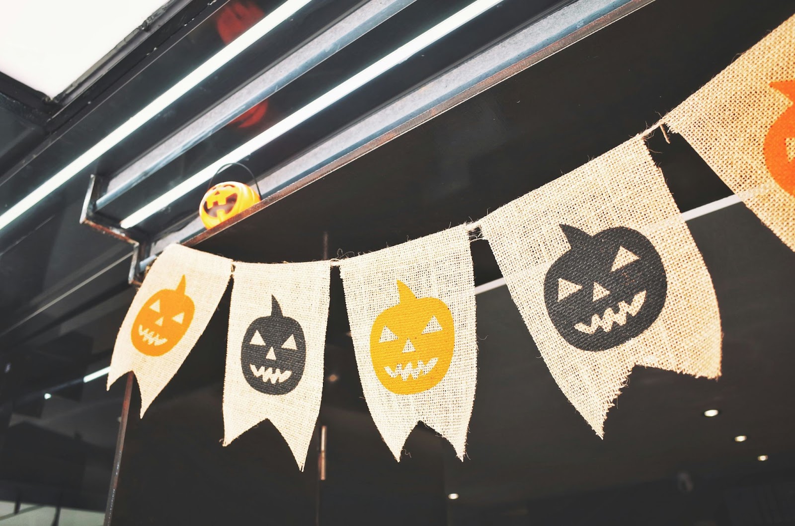 Striscione di Halloween in tweed con jack-o'-lantern neri e arancioni alternati appesi in uno spazio industriale.